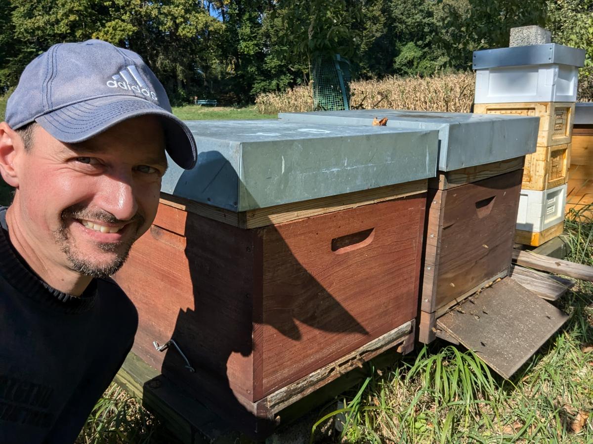 Imker Sebastian Pförtsch lächelnd neben seinen Bienenbeuten