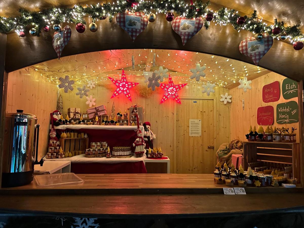 Unser beleuchteter Stand auf dem Christkindlmarkt mit Honig und Kerzen